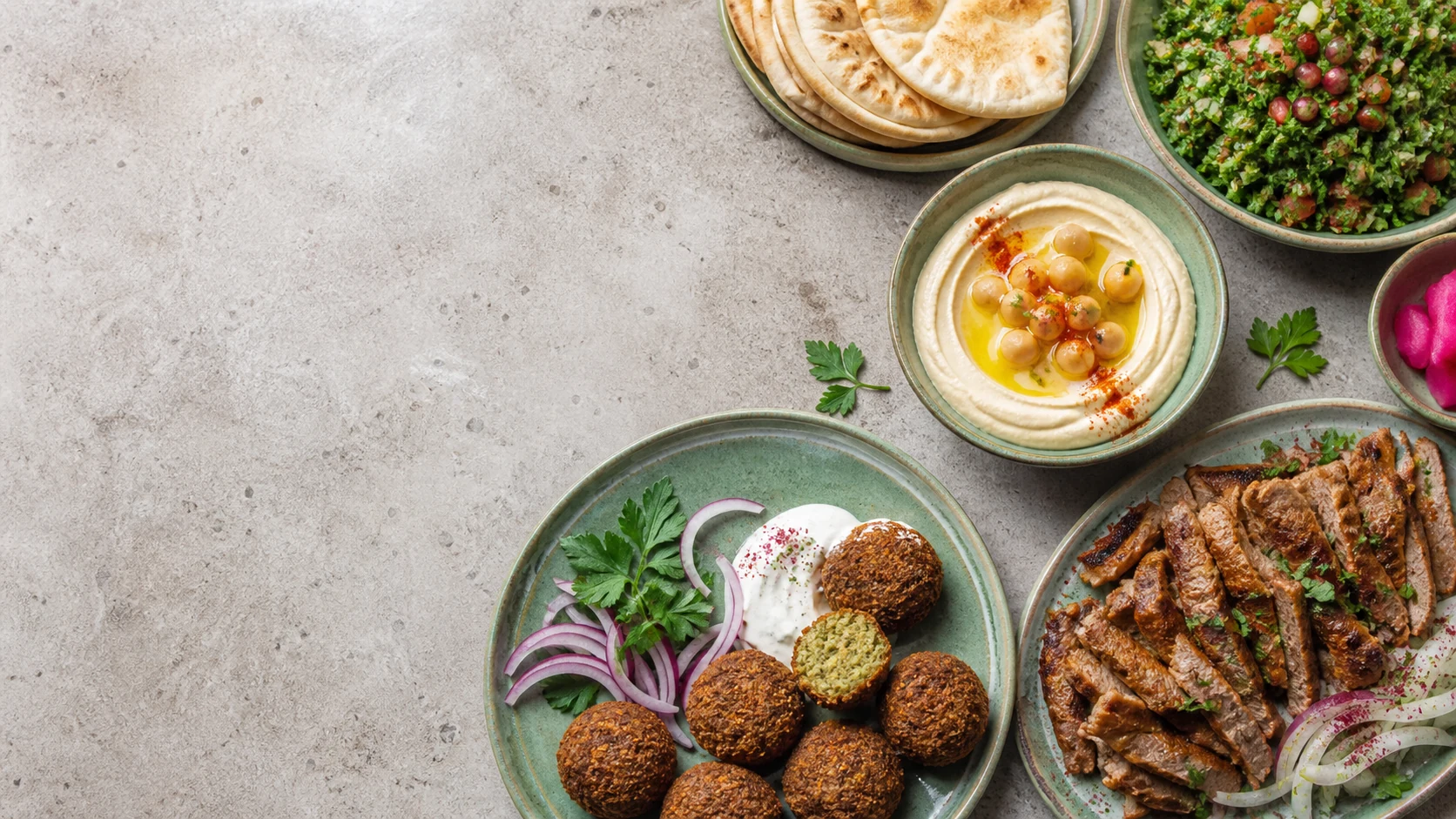 Falafel, Hummus und frische Kräuter auf einer hellen Tafel